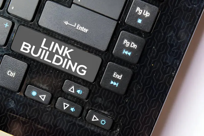 Close-up of a keyboard with the "Enter" key labeled as "LINK BUILDING." Other keys such as "Pg Up," "Pg Dn," and "End" are visible.